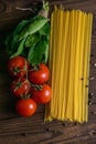 Vegetable pasta ingredients: spaghetti, peppers, tomatoes, basil, rosemary, olive oil, garlic, sea salt and spices on a dark Royalty Free Stock Photo