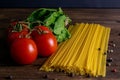 Vegetable pasta ingredients: spaghetti, peppers, tomatoes, basil, rosemary, olive oil, garlic, sea salt and spices on a dark Royalty Free Stock Photo