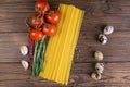 Vegetable pasta ingredients: spaghetti, peppers, tomatoes, basil, rosemary, olive oil, garlic, sea salt and spices on a dark Royalty Free Stock Photo