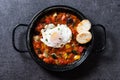 Vegetable pisto manchego with tomatoes, zucchini, peppers, onions,eggplant and egg, served in frying pan on black slate background