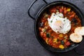 Vegetable pisto manchego with tomatoes, zucchini, peppers, onions,eggplant and egg, served in frying pan on black slate background