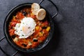 Vegetable pisto manchego with tomatoes, zucchini, peppers, onions,eggplant and egg, served in frying pan on black slate background