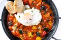 Vegetable pisto manchego with tomatoes, zucchini, peppers, onions,eggplant and egg, served in frying pan isolated on white