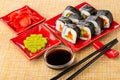 Vegetable rolls, ginger, wasabi, sushi sticks, bowl with soy sauce on mat