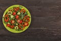 Vegetable salad with fresh tamata vegetables, cucumbers, lettuce, onions and arugula on a wooden table in a glass bowl. Vegetarian Royalty Free Stock Photo