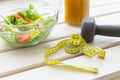 Vegetable salad and fruit smoothies and dumbbell lie on a white windowsill. Concept of healthy lifestyle physical Royalty Free Stock Photo