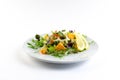 Vegetable salad with greens and pumpkin on a white plate on an isolated background, bright summer vegetables Royalty Free Stock Photo