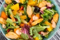 Vegetable salad with herbs, orange, cucumber, paprika on a green plate. Close-up