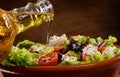 Vegetable salad with olive oil pouring from a bott