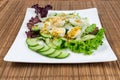 Vegetable salad with quail eggs on square dish close-up