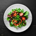 Vegetable salad with spinach, tomatoes, paprika and pumpkin seeds in a plate on a wooden background Top view. Royalty Free Stock Photo