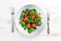 Vegetable salad with spinach, tomatoes, paprika and pumpkin seeds in a plate on a wooden background Top view. Royalty Free Stock Photo