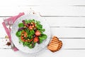 Vegetable salad with spinach, tomatoes, paprika and pumpkin seeds in a plate on a wooden background Top view. Royalty Free Stock Photo