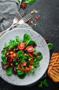 Vegetable salad with spinach, tomatoes, paprika and pumpkin seeds in a plate on a wooden background Top view. Royalty Free Stock Photo