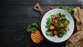 Vegetable salad with spinach, tomatoes, paprika and pumpkin seeds in a plate on a wooden background Top view. Free space for your Royalty Free Stock Photo