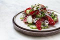 vegetable salad with tomato and cucumber, red onion, hot peppers, walnuts, a traditional Georgian dish, on a marble table Royalty Free Stock Photo