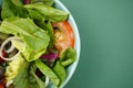 Vegetable salad. Vegan, vegetarian healthy, diet nutrient meal in green bowl on green paper background. Royalty Free Stock Photo