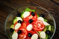 Vegetable salad on a wooden background. Lettuce, tomato, cucumber, olives, mozzarella and olive oil. Wholesome healthy food Royalty Free Stock Photo