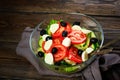 Vegetable salad on a wooden background. Lettuce, tomato, cucumber, olives, mozzarella and olive oil. Wholesome healthy food Royalty Free Stock Photo