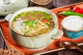 Vegetable soup, broth with noodles, herbs, parsley and vegetables in bowl with sour cream, spice, pepper, dried thyme and bread