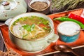 Vegetable soup, broth with noodles, herbs, parsley and vegetables in bowl with sour cream, spice, pepper, dried thyme