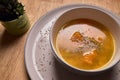 Vegetable soup or broth with pumpkin and chickpeas in a bowl. fine spreading herbs. solid wood background. Healthy, vegan and diet