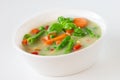 Vegetable soup with carrots and green beans and basil in white ceramic bowl on light background Royalty Free Stock Photo