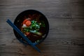 Vegetable soup in ceramic bowl on wooden table. Chinese soup served with sticks. Eastern soup bowl top view photo