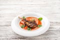 Vegetable soup with tomatoes in a restaurant close-up. Lamb soup on bone noodles on a white plate and copy space Royalty Free Stock Photo