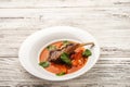 Vegetable soup with tomatoes in a restaurant close-up. Lamb soup on bone noodles on a white plate and copy space