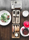 Vegetable spring salad on white porcelain plate and soup in red pot on textured wooden table in cafe with modern trendy Royalty Free Stock Photo