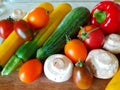 Vegetable still life on a cutting board. Close-up. Zucchini, tomatoes, champignons, peppers. Red, yellow, orange.