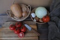 Vegetable stocks are laid out on wooden shelf, ripe red tomatoes, head of cabbage in basket, garlic, pumpkin, onions, old dishes,