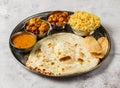 Vegetable thali set with plain biryani, mixed vegetable of aloo gobi matar, chanay, shorba and chapati served in dish isolated on