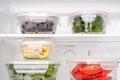 Vegetables and berries in glass boxes in the refrigerator close-up
