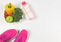 Vegetables capsicum, broccoli, tomatoes and apple in heart shape plate, pink sneakers or sport shoes and bottle of water on