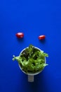 Vegetables in cup on blue background, minimalist photography