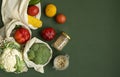 Vegetables in eco bag and nuts in a glass jar on green surface. Pepper, tomato, corn, cucumber, broccoli, cauliflower in Royalty Free Stock Photo