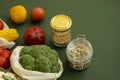 Vegetables in eco bag and nuts in a glass jar on green surface. Pepper, tomato, corn, cucumber, broccoli, cauliflower in Royalty Free Stock Photo