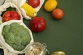 Vegetables in eco bag and nuts in a glass jar on green surface. Pepper, tomato, corn, cucumber, broccoli, cauliflower in Royalty Free Stock Photo