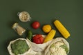 Vegetables in eco bag and nuts in a glass jar on green surface. Pepper, tomato, corn, cucumber, broccoli, cauliflower in Royalty Free Stock Photo