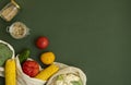 Vegetables in eco bag and nuts in a glass jar on green surface. Pepper, tomato, corn, cucumber, broccoli, cauliflower in Royalty Free Stock Photo