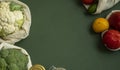 Vegetables in eco bag and nuts in a glass jar on green surface. Pepper, tomato, corn, cucumber, broccoli, cauliflower in Royalty Free Stock Photo