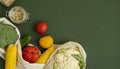 Vegetables in eco bag and nuts in a glass jar on green surface. Pepper, tomato, corn, cucumber, broccoli, cauliflower in Royalty Free Stock Photo