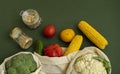 Vegetables in eco bag and nuts in a glass jar on green surface. Pepper, tomato, corn, cucumber, broccoli, cauliflower in Royalty Free Stock Photo