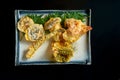 Vegetables fried in tempura, served in a white plate. Deep-fried asparagus, broccoli and mushrooms. Isolated over black background