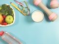 Vegetables and fruit in heart shape plate, bottle of water, measure tape,  pink dumbbells and milk on blue background. Healthy Royalty Free Stock Photo