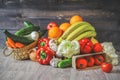 Vegetables and fruits on a graphite wooden background: in a box are tomatoes, cucumber, garlic, large red peppers, Iceberg lettuce Royalty Free Stock Photo