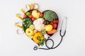 vegetables and fruits laying in heart shaped dish near stethoscope and measuring tape Royalty Free Stock Photo
