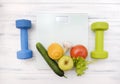 Vegetables and fruits on scales, 2 dumbbells on a white wooden background Royalty Free Stock Photo